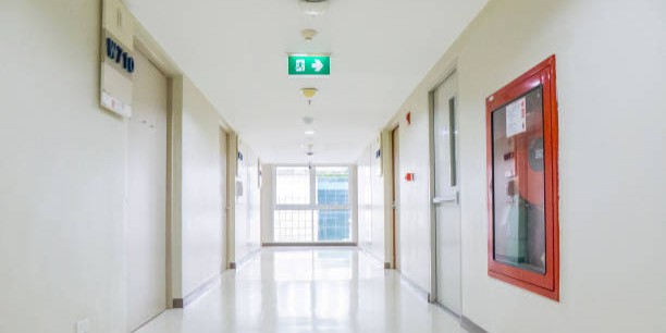 Modern and clean hospital corridor with smoke detector, fire exit sign and fire hose reel cabinet
